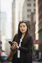 Chinese businesswoman texting on cell phone in city