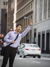 Chinese businessman hailing taxi in city