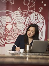 Chinese businesswoman writing in notebook in restaurant