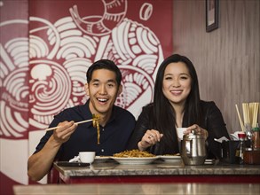 Smiling Chinese couple posing in restaurant