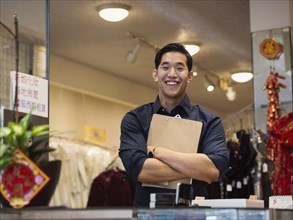 Smiling Chinese man posing with clipboard in store