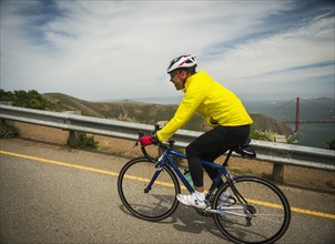 Hispanic man riding bicycle on waterfront road