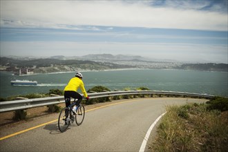 Hispanic man riding bicycle on waterfront road