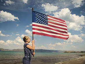 Caucasian girl holding American flag at beach
