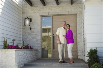 Older couple posing on front stoop of house