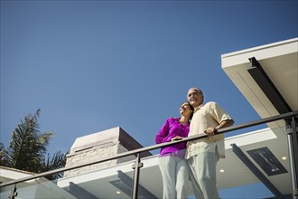 Smiling couple standing on modern balcony