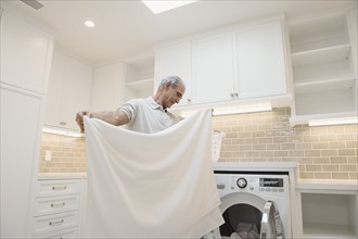 Caucasian man folding towel in modern laundry room