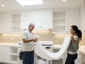 Couple folding towel in modern laundry room