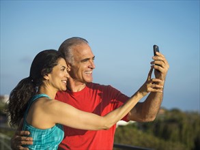 Older couple posing for cell phone selfie