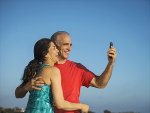 Older couple laughing and posing for cell phone selfie
