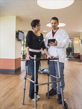 Caucasian physical therapist showing digital tablet to patient