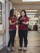 Nurses reading clipboard in hospital corridor