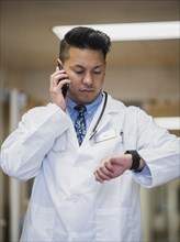 Filipino doctor talking on cell phone and checking the time