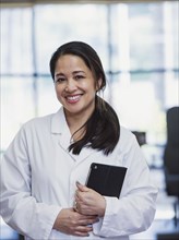 Portrait of smiling Asian physical therapist holding digital tablet