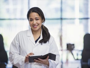 Portrait of smiling Asian physical therapist using digital tablet