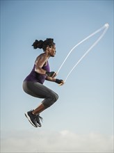 Black woman jumping rope in sky
