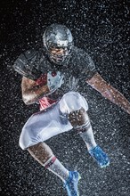 Water splashing on black football player jumping
