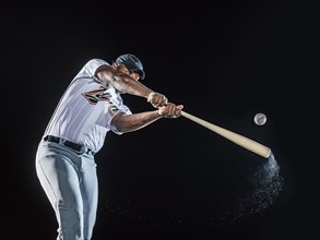 Water splashing from swinging bat of black baseball player
