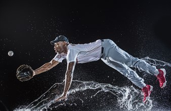 Water splashing on diving black baseball player