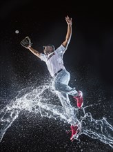 Water splashing on jumping black baseball player