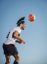 Hispanic man heading soccer ball