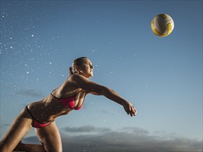 Caucasian woman diving to volleyball