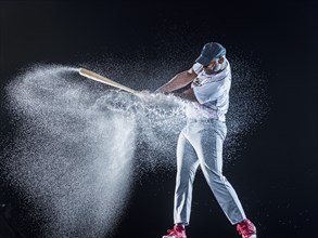 Water splashing on Black baseball player swinging bat