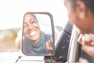 Reflection of African American woman in car mirror