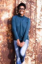 Smiling African American woman leaning on rusty metal wall