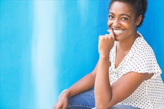 African American woman smiling near blue wall