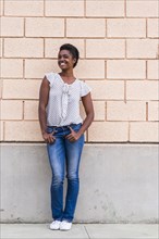 Smiling African American woman posing near concrete wall