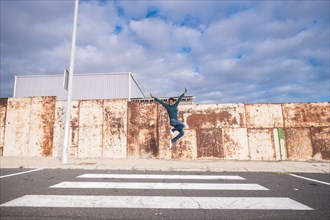 African American woman jumping for joy in crosswalk