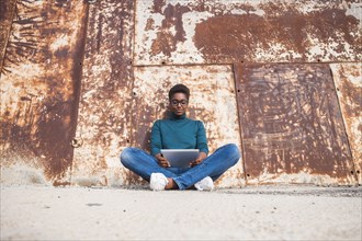 African American woman sitting on ground using digital tablet