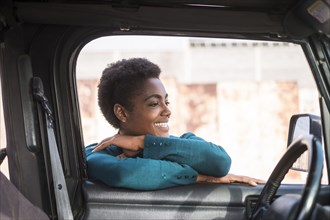 Smiling African American woman leaning on car window