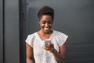 Smiling African American woman texting on cell phone