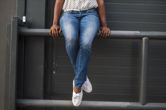 Legs of African American woman sitting on railing