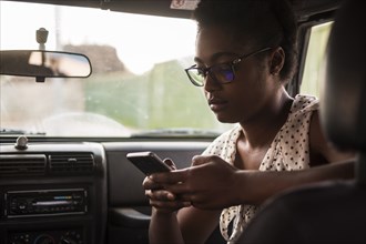 Serious African American woman texting on cell phone in car