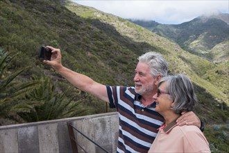 Older Caucasian couples posing for cell phone selfie