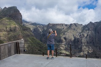 Older Caucasian man photographing mountains with cell phone