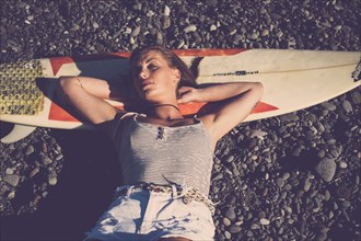 Caucasian woman laying on surfboard on beach