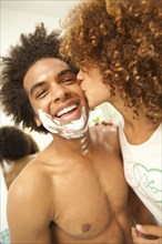 Girlfriend kissing boyfriend's shaving cream-covered face