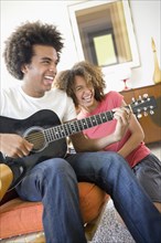 Woman laughing while boyfriend plays guitar