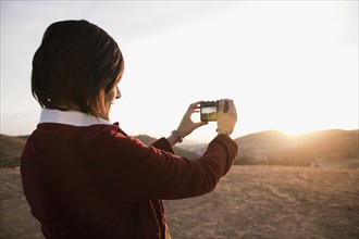Hispanic woman photographing the sunset