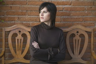 Frustrated Hispanic woman sitting on bench