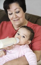 Hispanic grandmother feeding baby