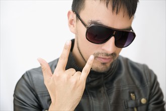 Hispanic man in sunglasses and leather coat gesturing