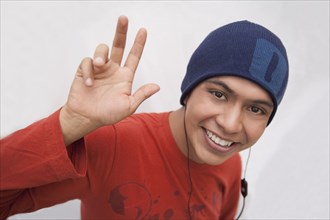 Hispanic man in cap listening to headphones and waving