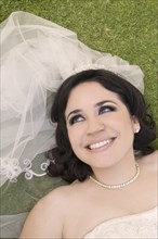 Hispanic bride laying in grass