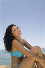 Hispanic woman sitting on beach