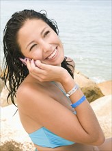 Hispanic woman on beach talking on cell phone
